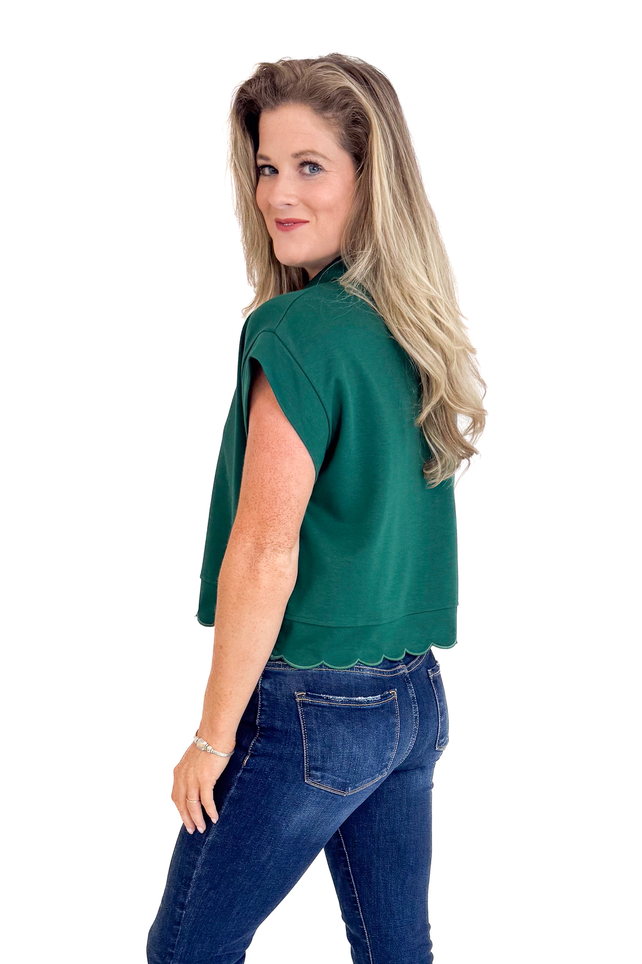 Woman wearing a green top and blue jeans on a white background