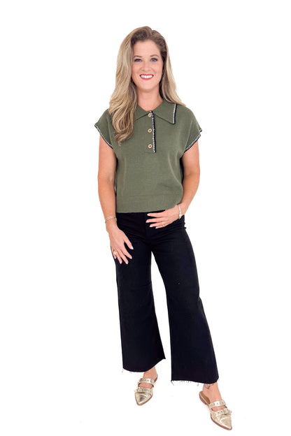 Woman wearing a green cap-sleeve top and black pants on a white background