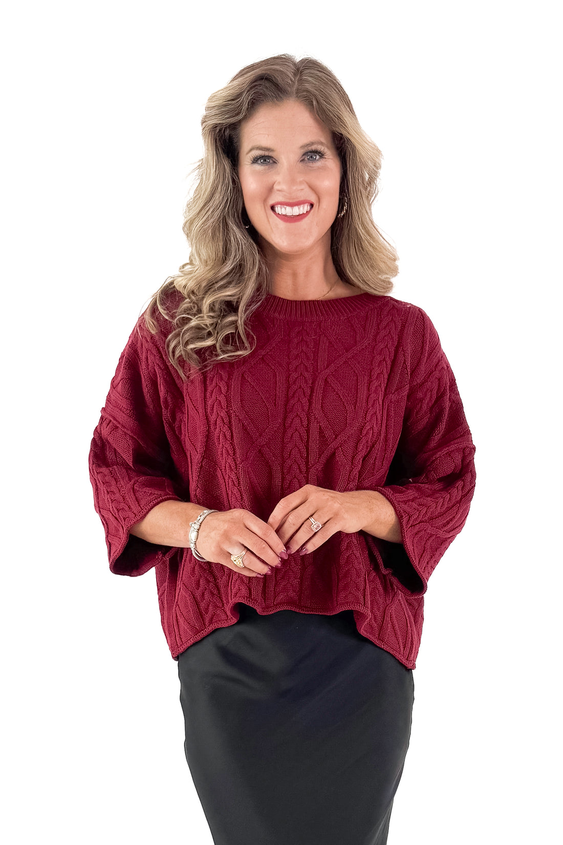 Front view of woman wearing Burgundy Cable Knit 3/4 Sleeve Sweater with black skirt against white studio background.