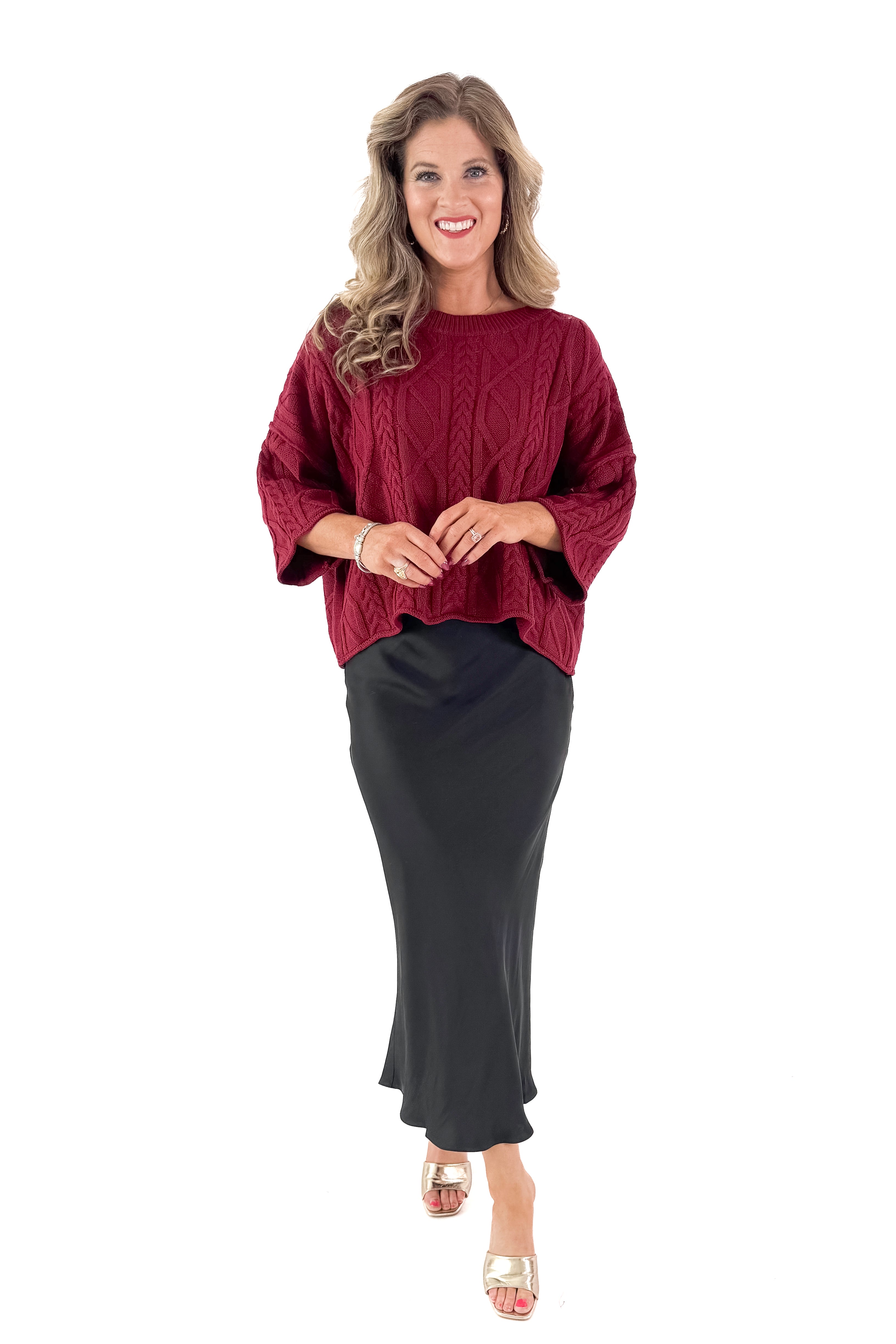 Front view of woman wearing Burgundy Cable Knit 3/4 Sleeve Sweater with black skirt against white studio background.