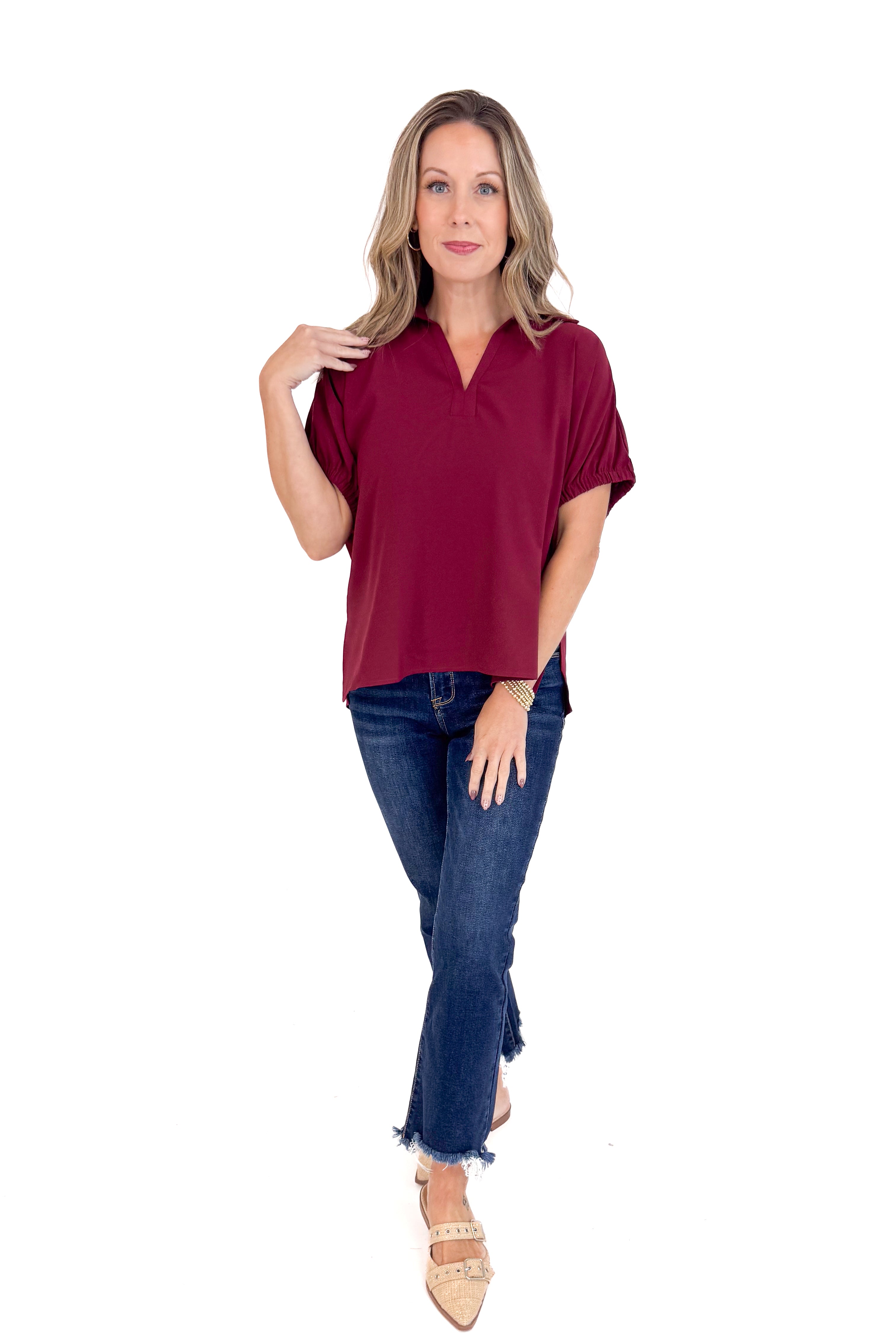 Woman wearing a burgundy top and blue jeans on a white background