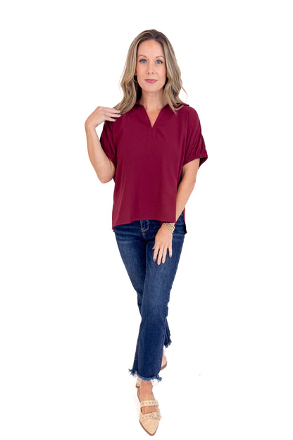 Woman wearing a burgundy top and blue jeans on a white background