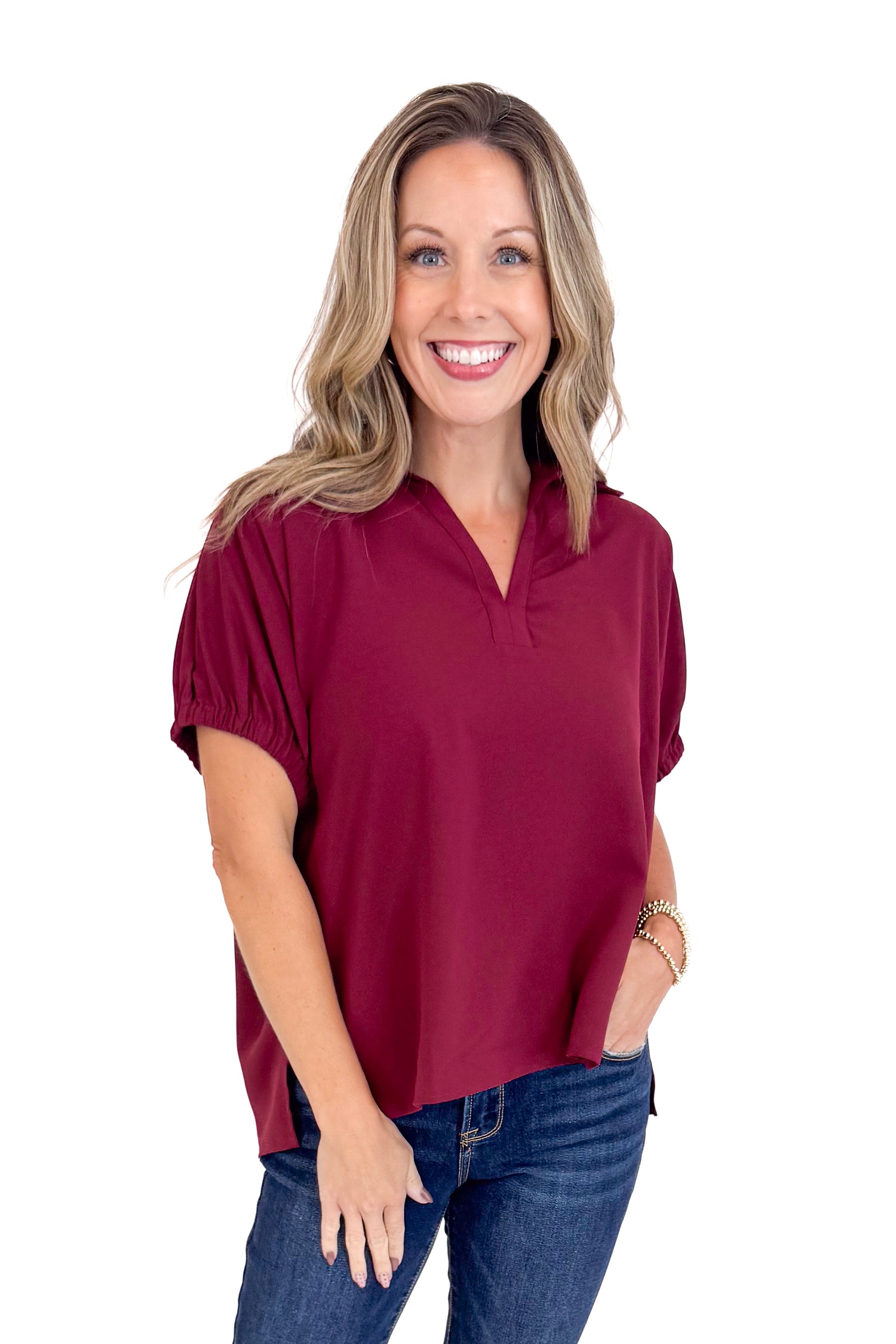 Woman wearing a maroon blouse and blue jeans on a white background