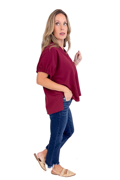 Woman wearing a burgundy top and blue jeans on a white background