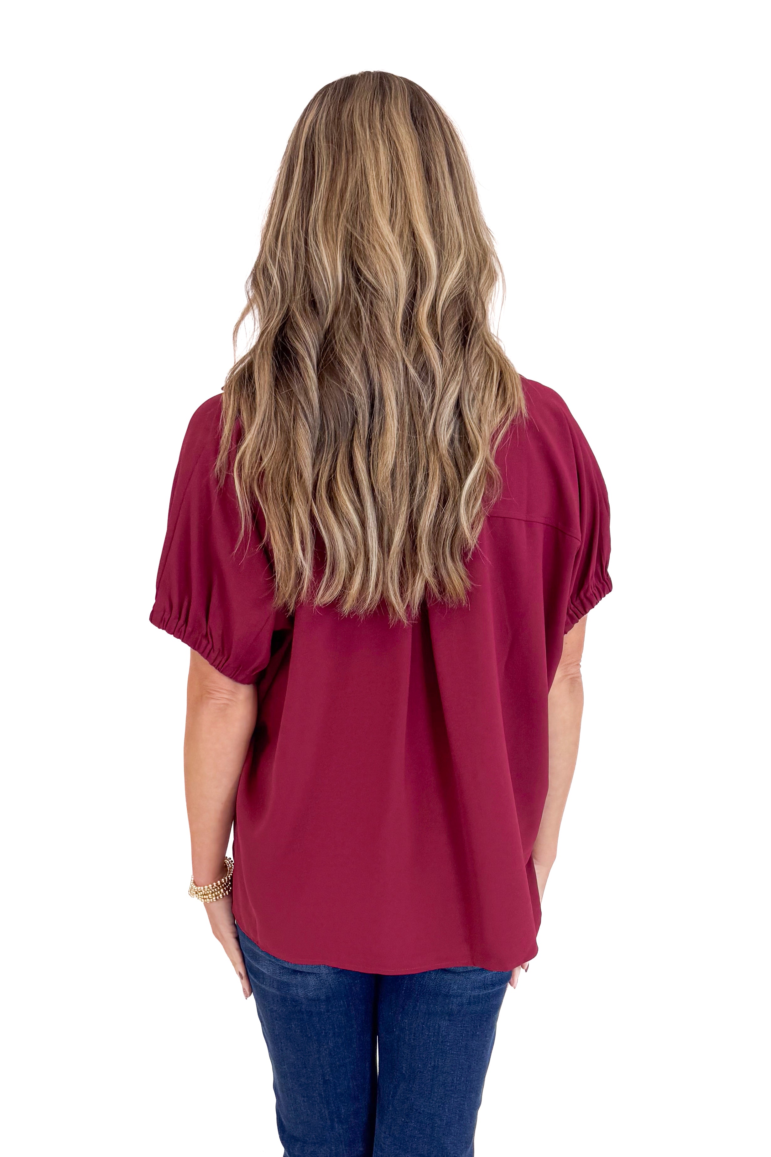 Person wearing a burgundy top with long hair on a white background