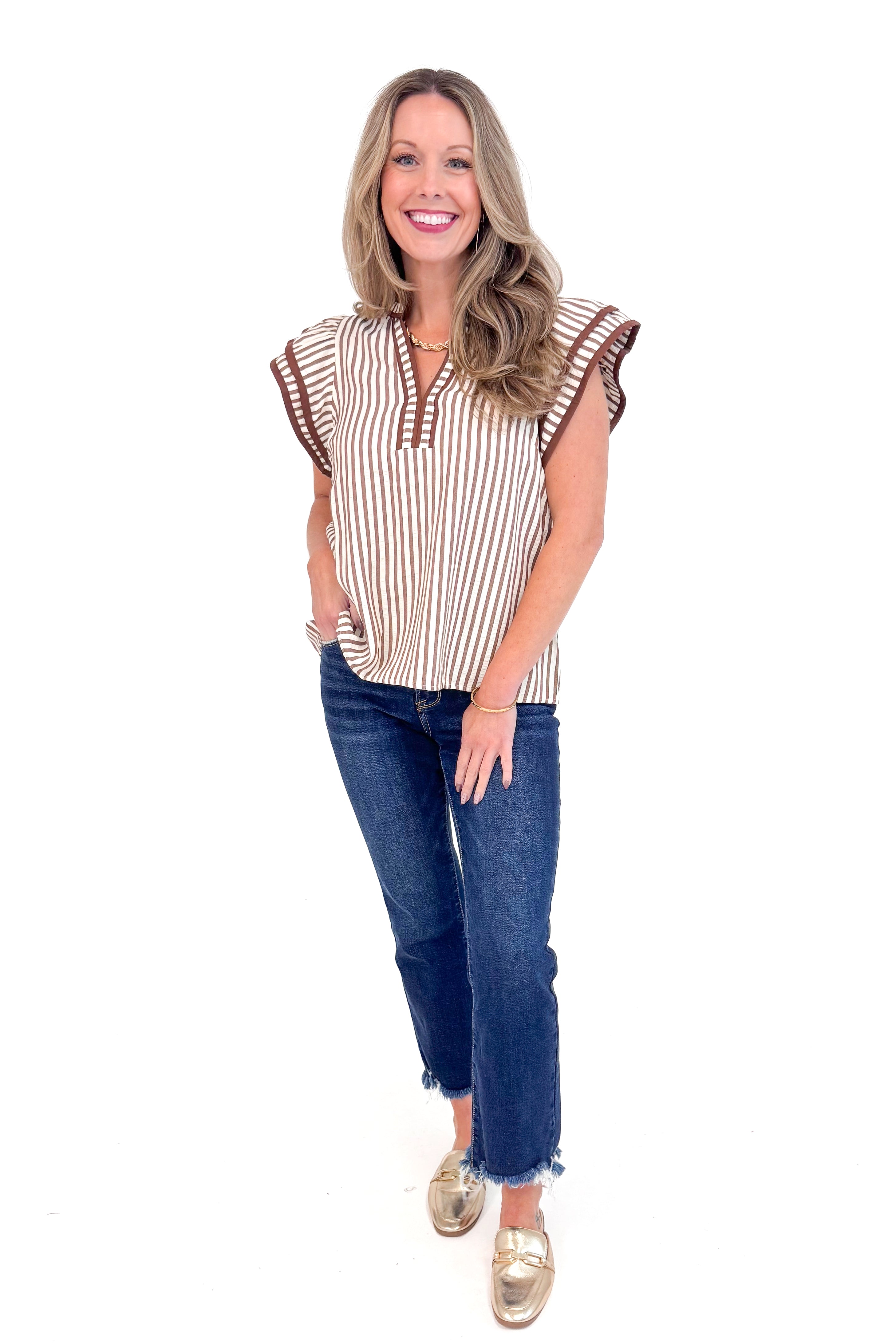 Woman wearing Rise &amp; Shine Brown Striped Flutter Sleeve Top by Entro and jeans against white studio background.