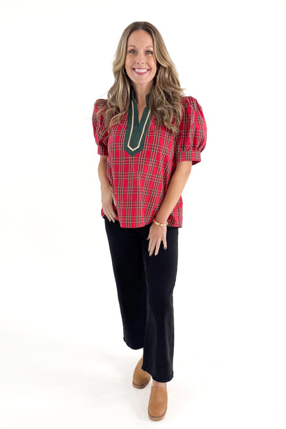 Front view of woman wearing Red Tartan With Green V-neck Detail Top with jeans against white studio background.