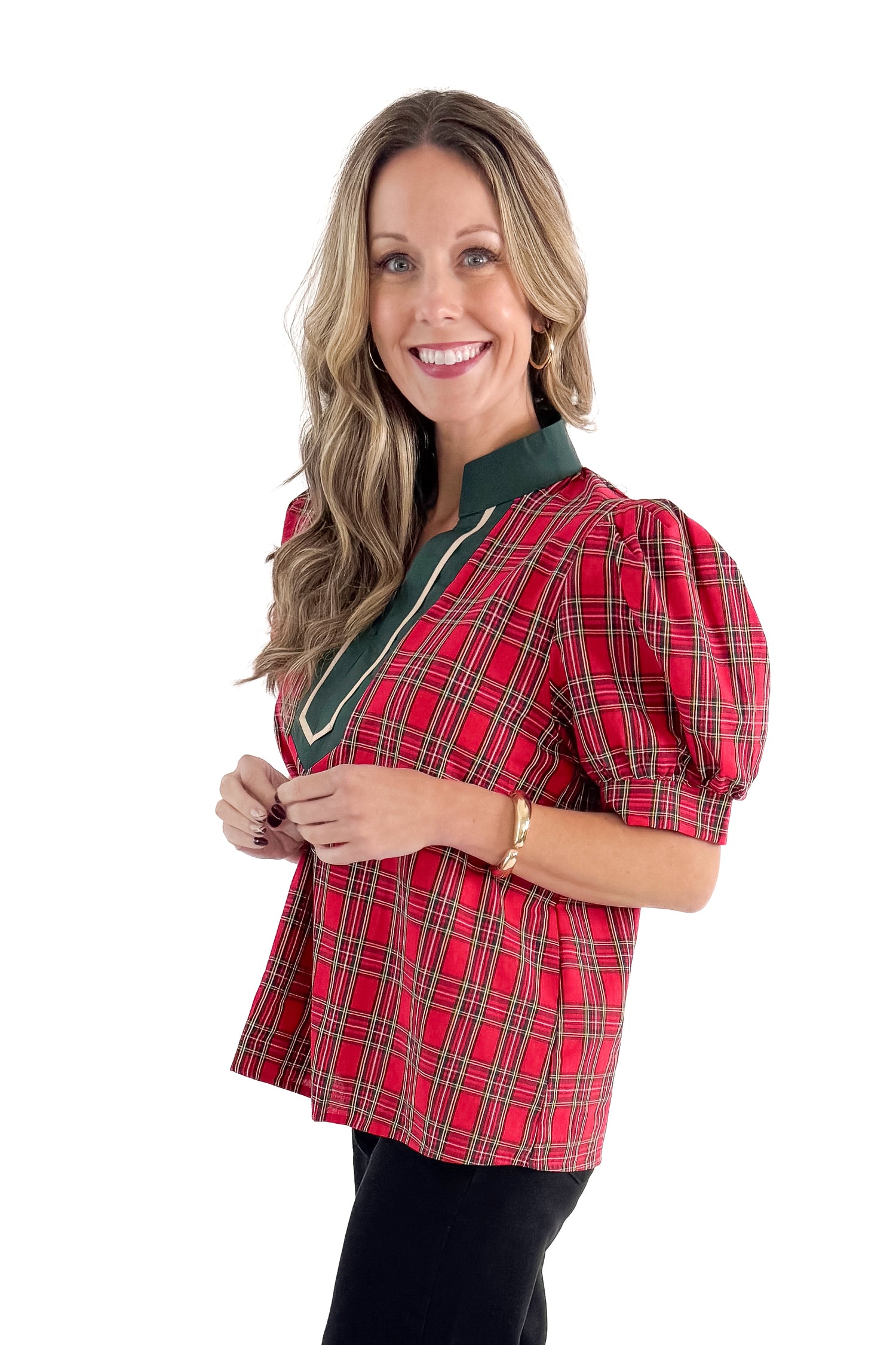 Side view of woman wearing Red Tartan With Green V-neck Detail Top with jeans against white studio background.
