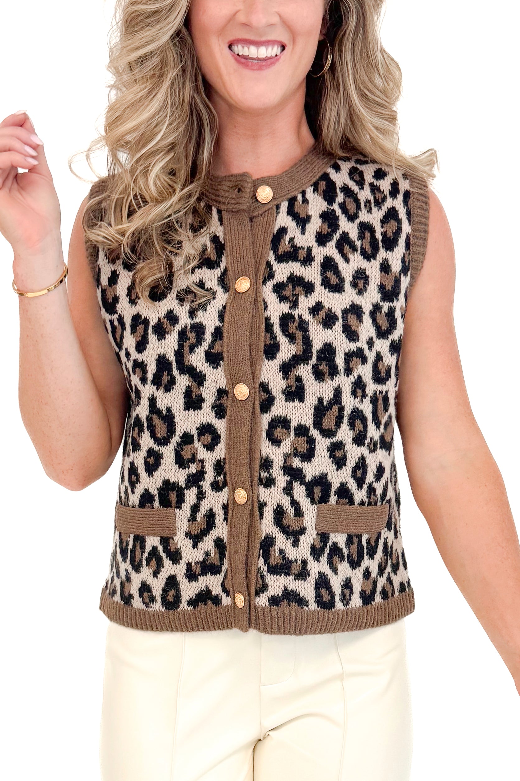 Detailed view of Woman wearing leopard print button up sweater vest with gold buttons and contrast trim.