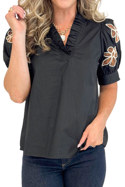 Detailed front view of black short sleeve top showing floral embroidered design.
