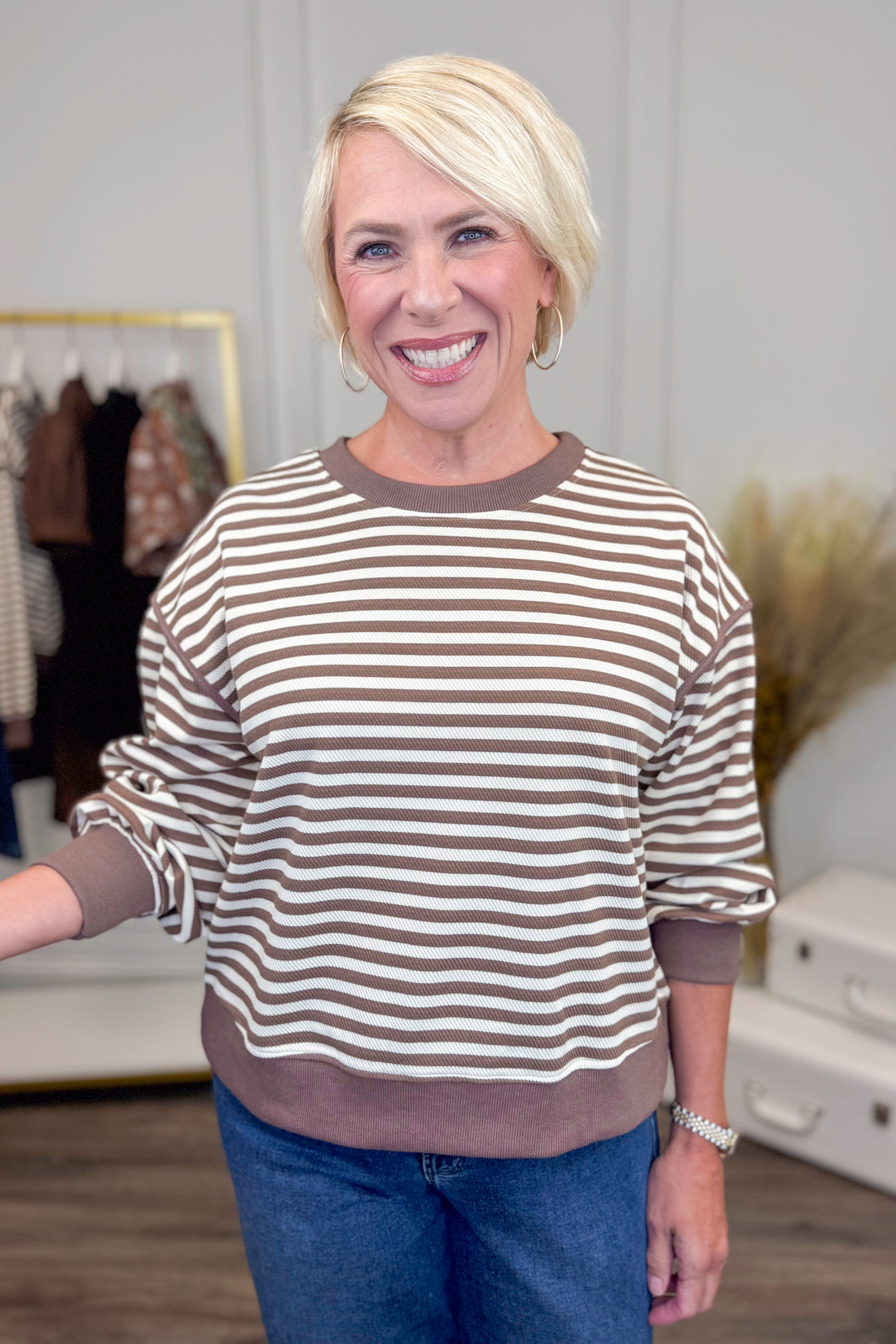 Woman wearing a striped sweater and blue jeans in an indoor setting