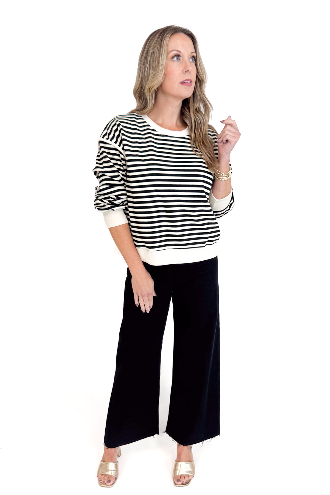 Woman wearing a black and white striped sweater and black pants on a white background