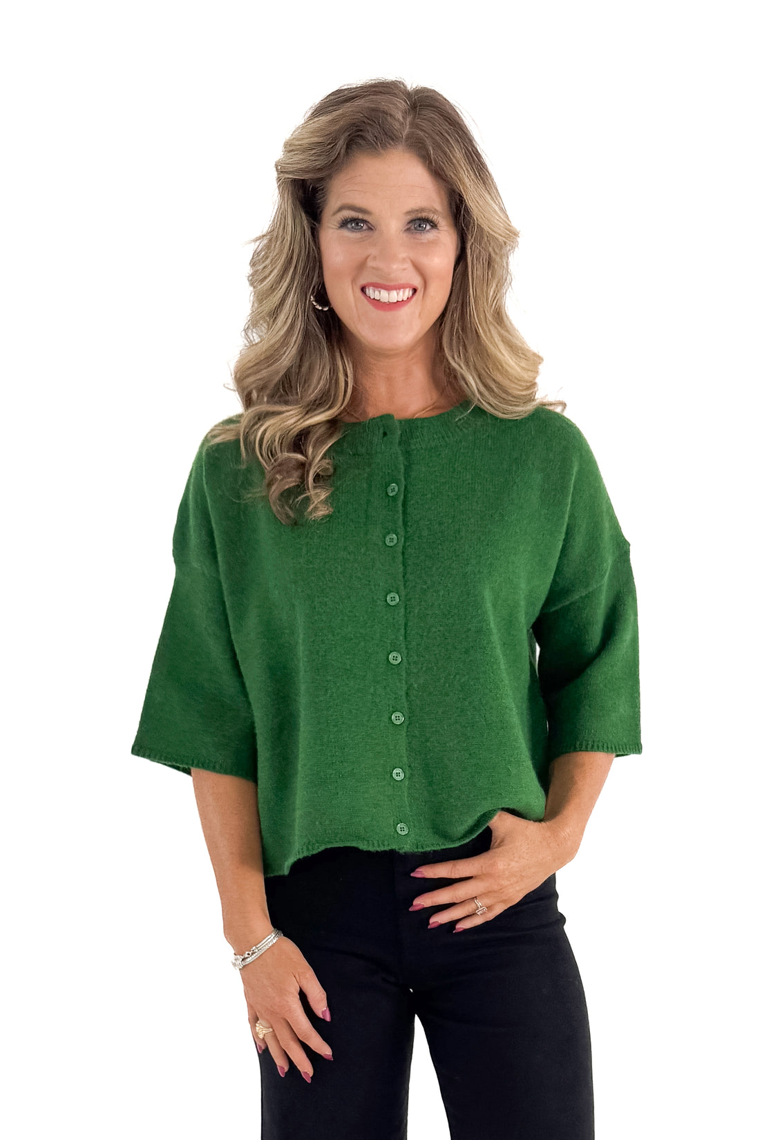 Front view of woman wearing green sweater with jeans against white studio background.
