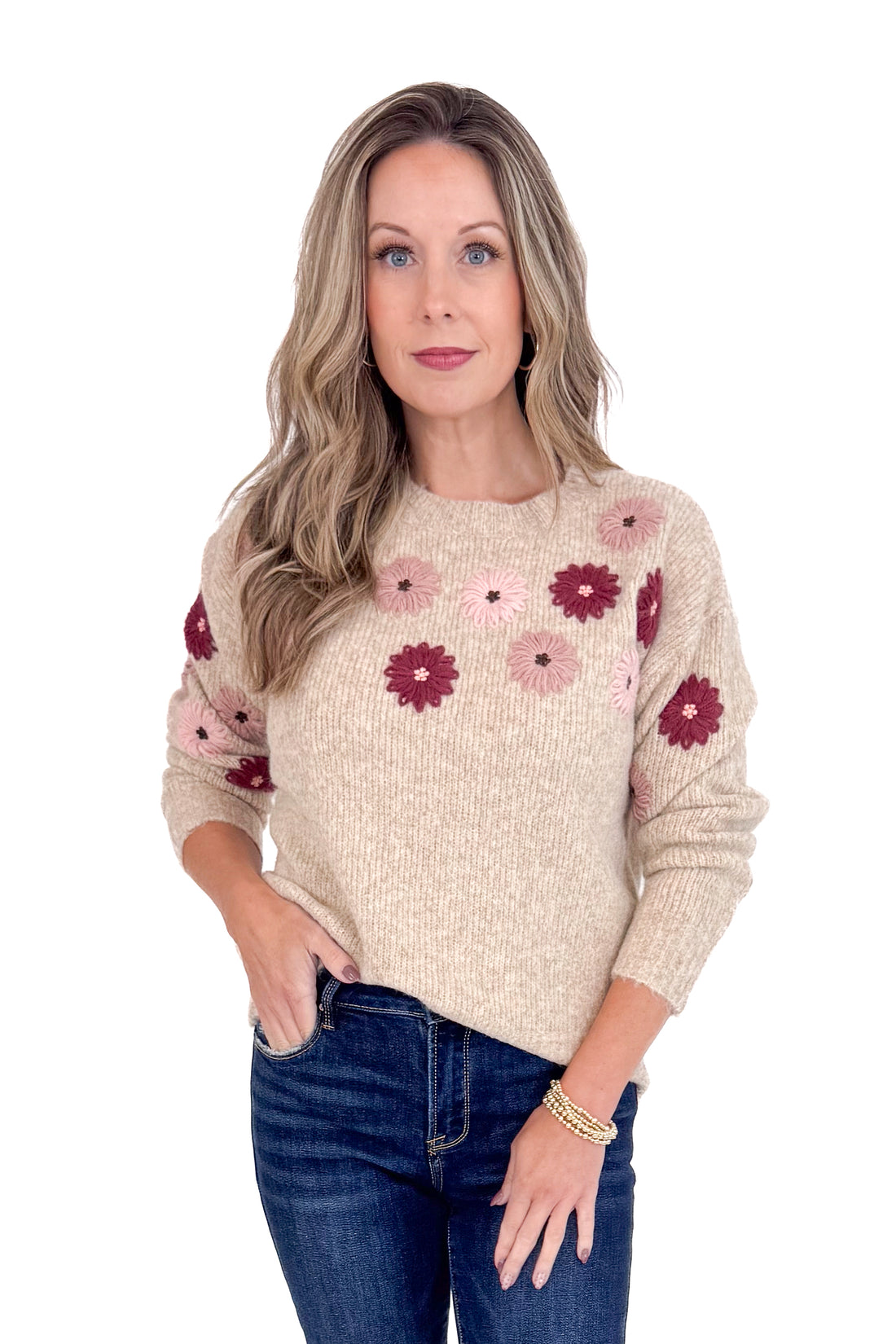 Woman wearing a beige sweater with floral patterns on a white background