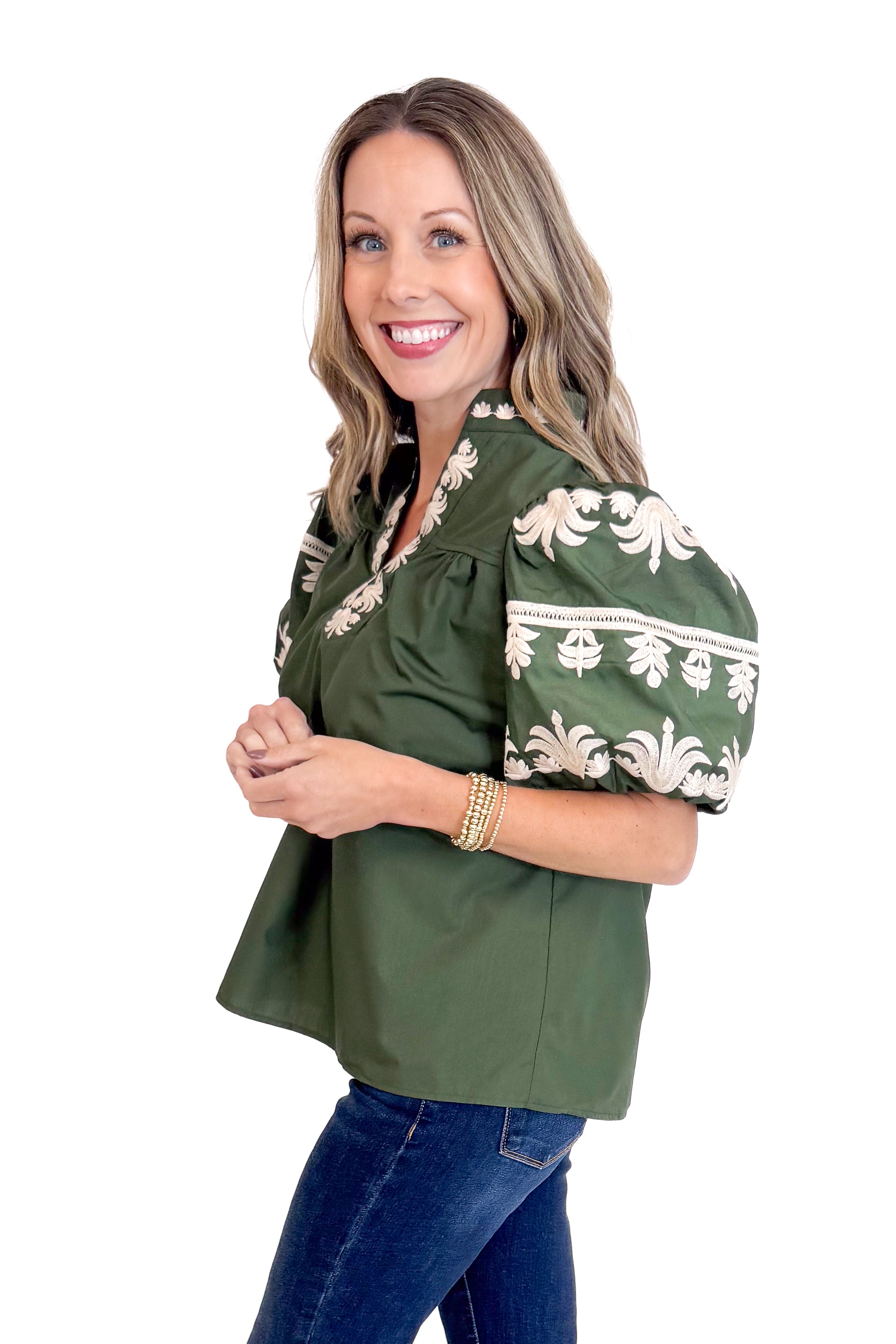 Woman wearing a green blouse with white embroidery on a white background