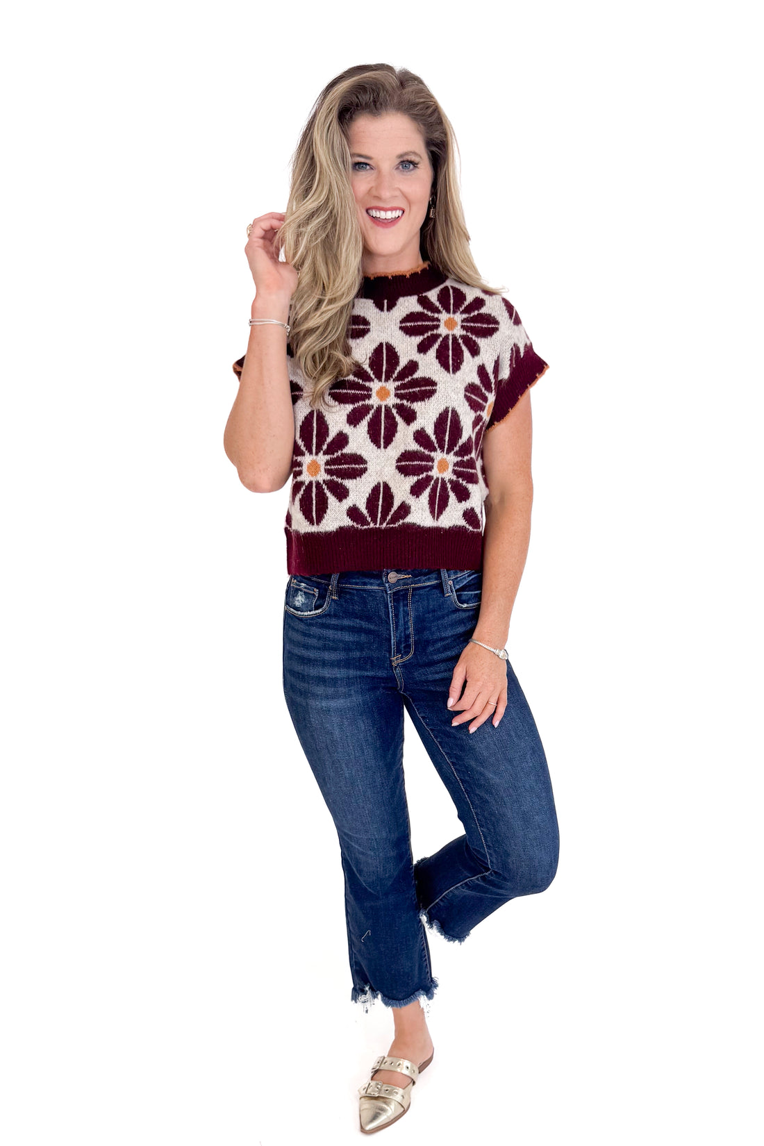 Woman wearing a patterned top and jeans on a white background