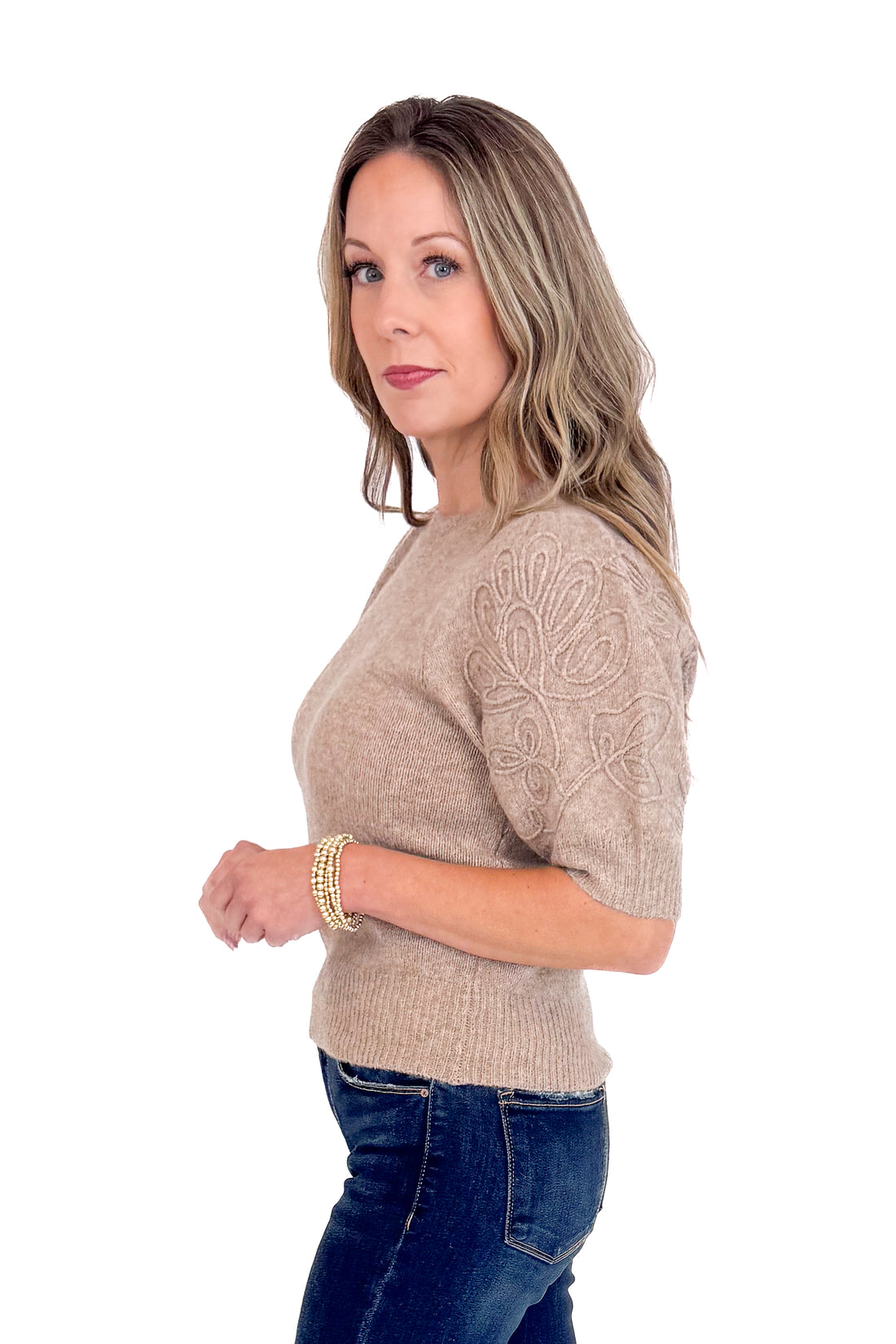 Woman wearing a beige sweater with lace details on a white background