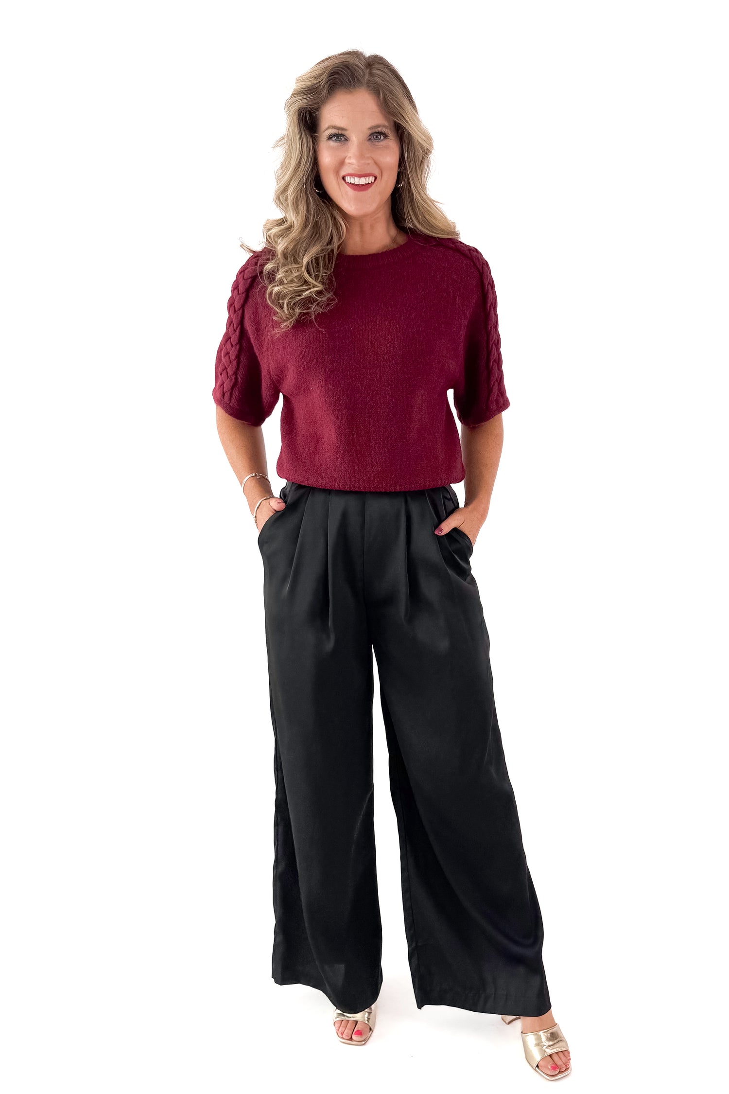 Front view of woman wearing Burgundy Braid Detail Short Sleeve Sweater with black pants against white studio background.