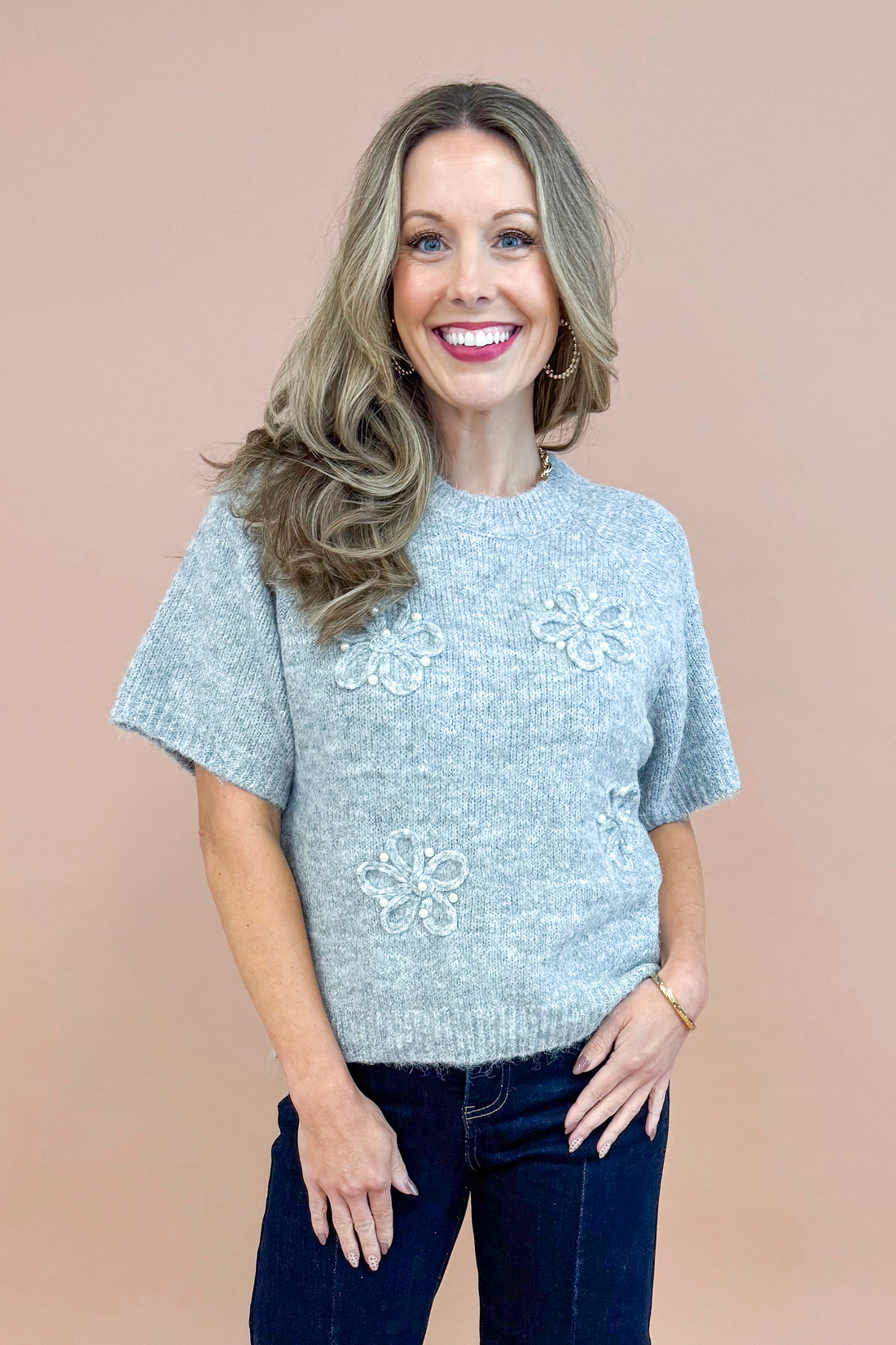 Front view of woman wearing Grey Floral & Pearl Detail Short Sleeve Sweater by Entro and blue jeans.