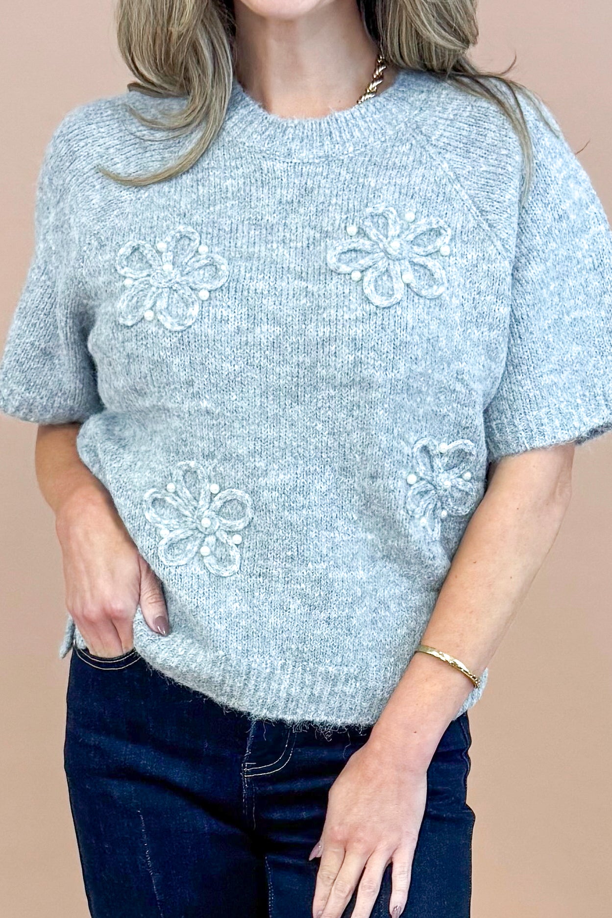 Detailed front view of woman wearing Grey Floral &amp; Pearl Detail Short Sleeve Sweater by Entro and blue jeans. 