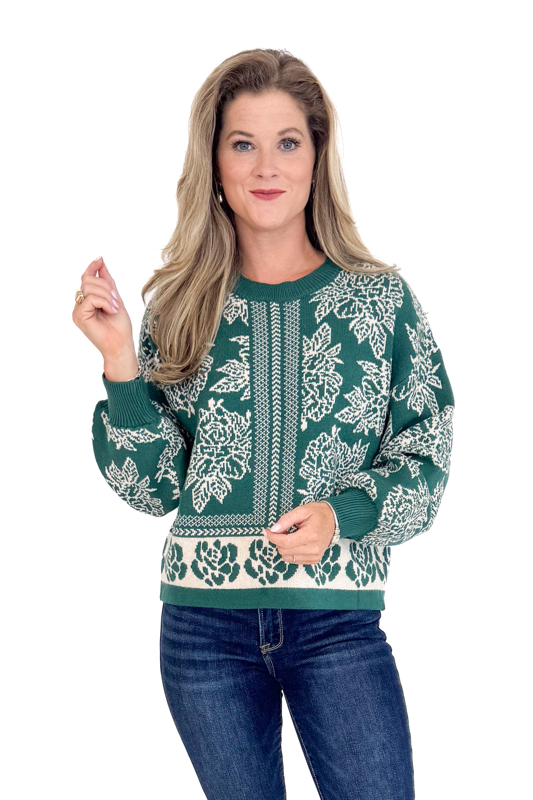 Woman wearing a green sweater with white floral patterns on a white background