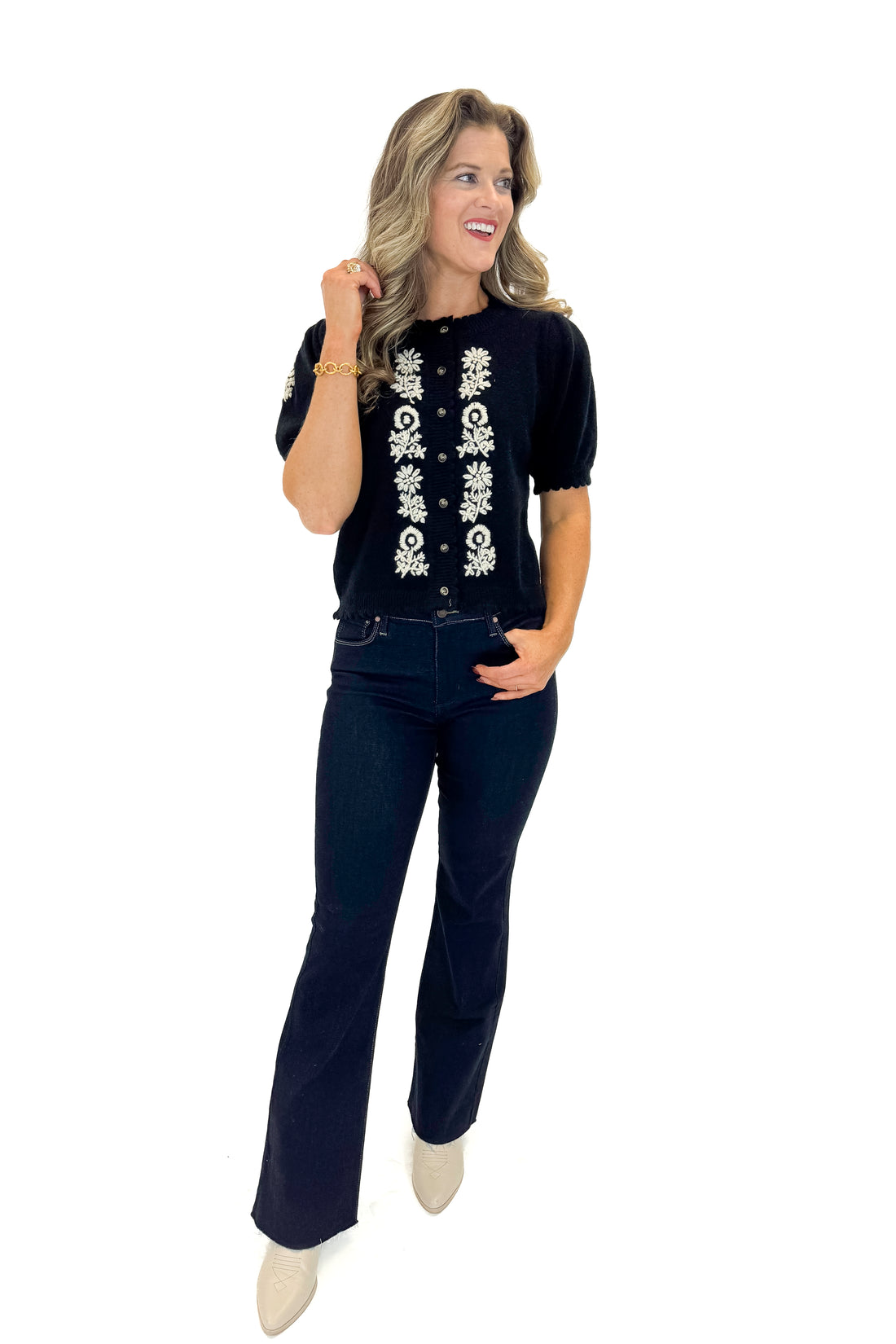 Front view of woman wearing Black Center Embroidered Short Sleeve Cardigan with jeans against white studio background.