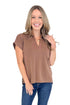 Front view of woman wearing coffee color top with jeans against white studio background.