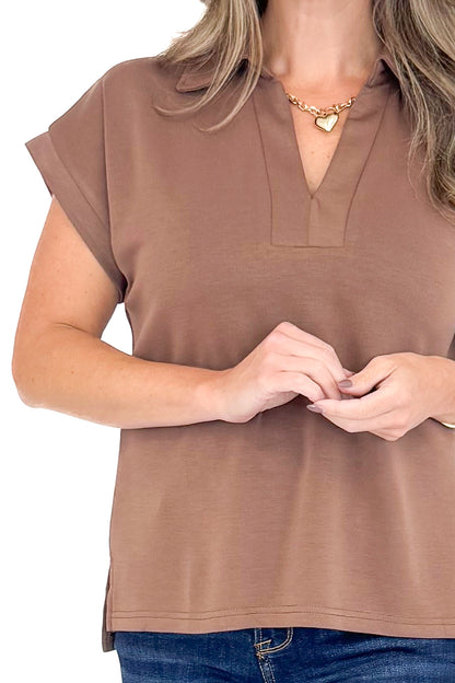 Front detail view of woman wearing coffee color top with jeans against white studio background.