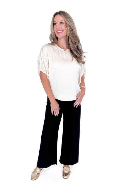 Front view of woman wearing Champagne Satin Tie Sleeve Top with jeans against white studio background.