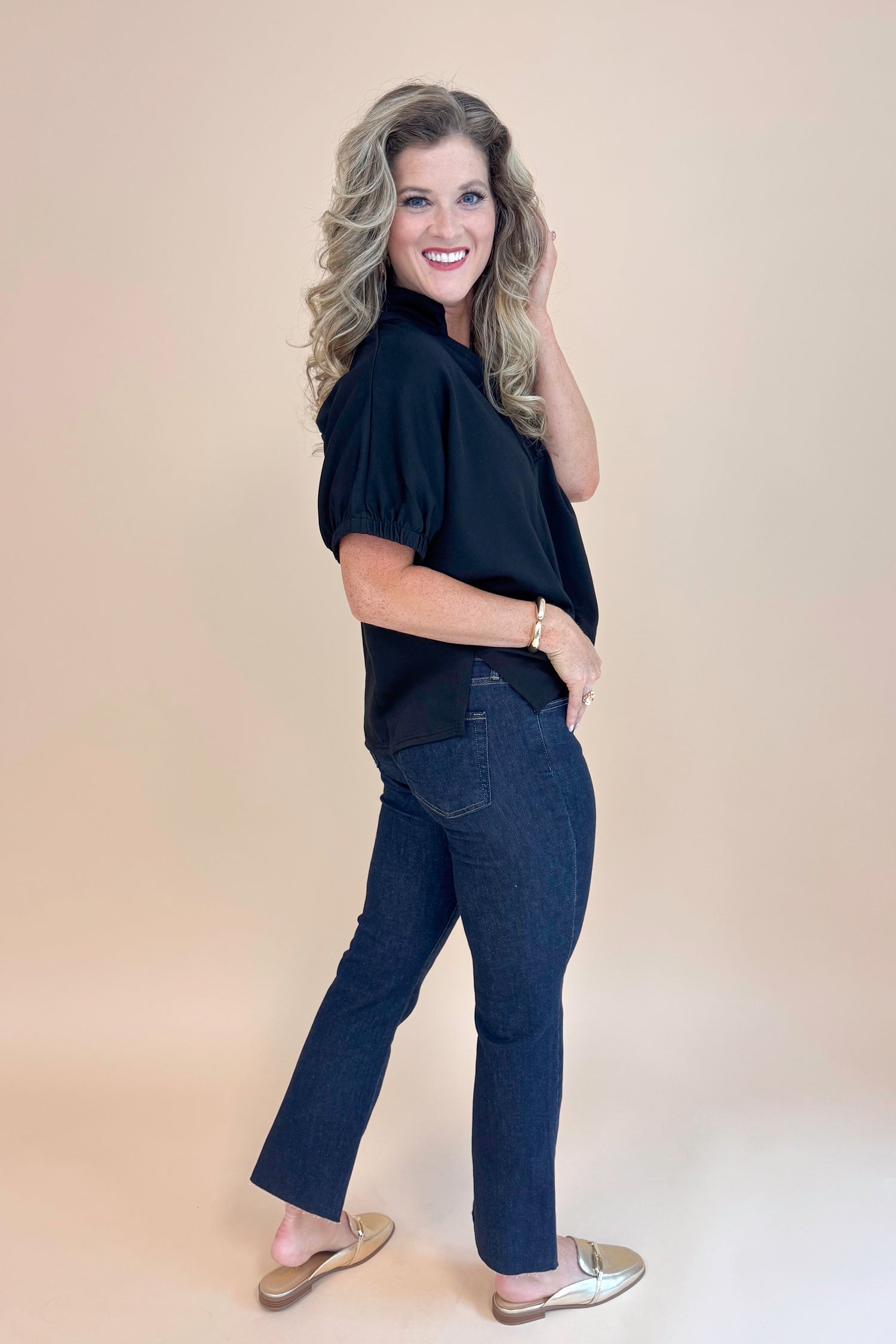 Side full view of Black Collared V-neck Top by Entro and blue jeans. 