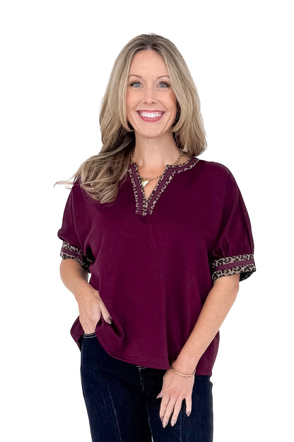 Front view of woman wearing burgundy top with jeans against white studio background.
