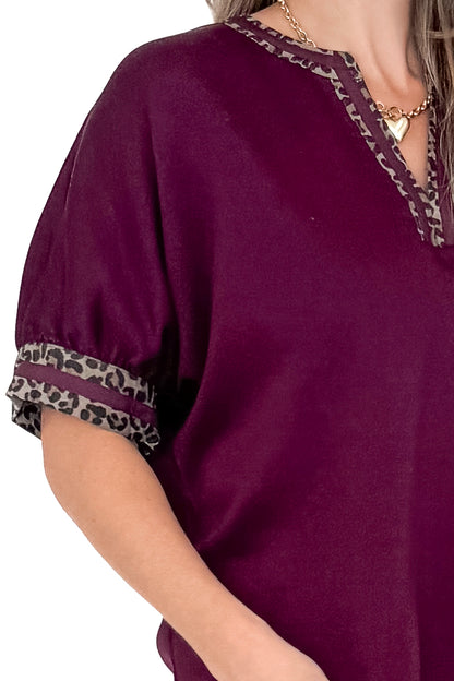Front detail view of woman wearing burgundy top against white studio background.