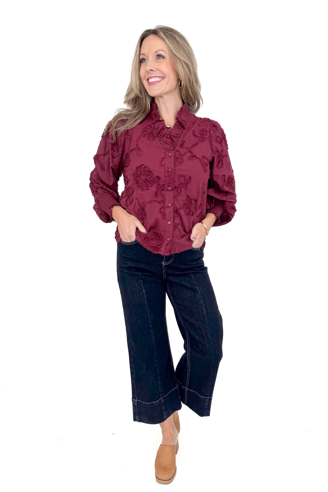 Front view of woman wearing button down top with jeans against white studio background.