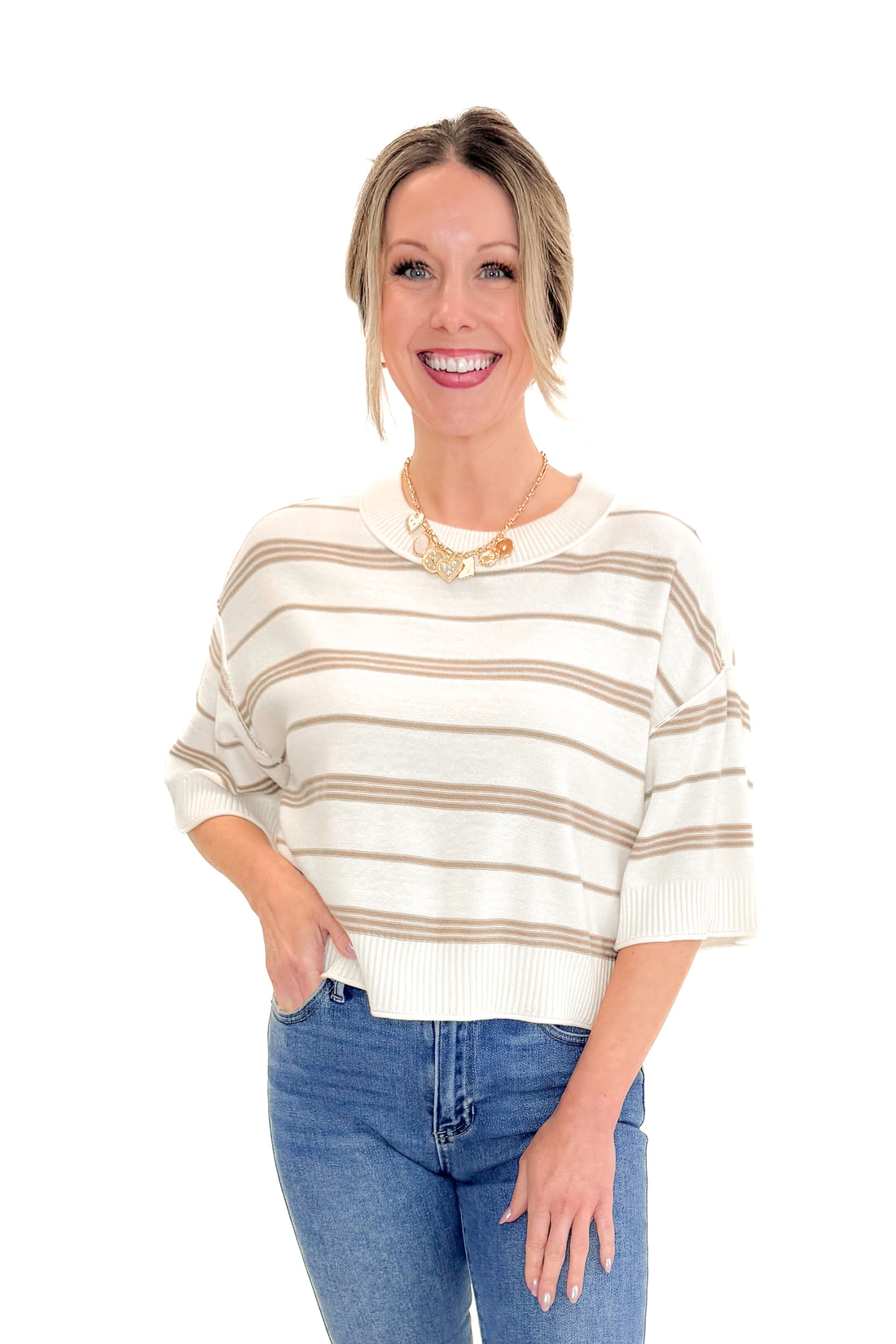 Front view of woman wearing Cream &amp; Tan Striped Short Sleeve Sweater by Entro with jeans against white studio background.
