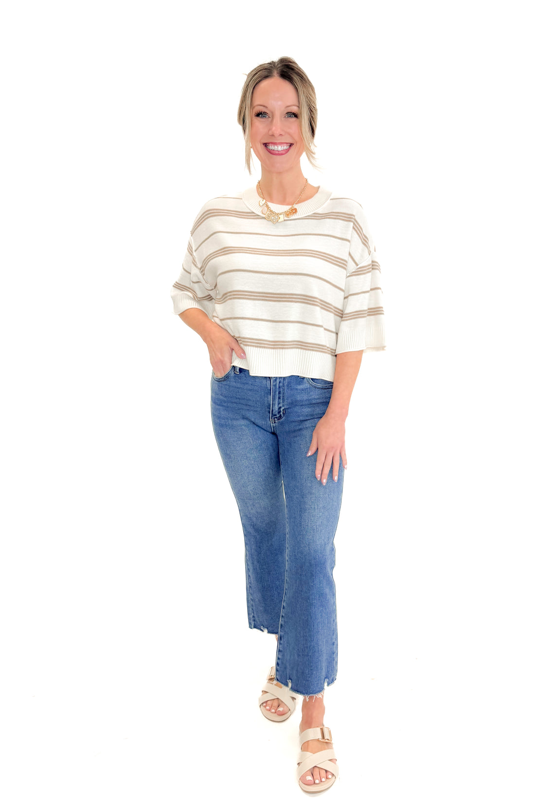Front view of woman wearing Cream &amp; Tan Striped Short Sleeve Sweater by Entro with jeans against white studio background.