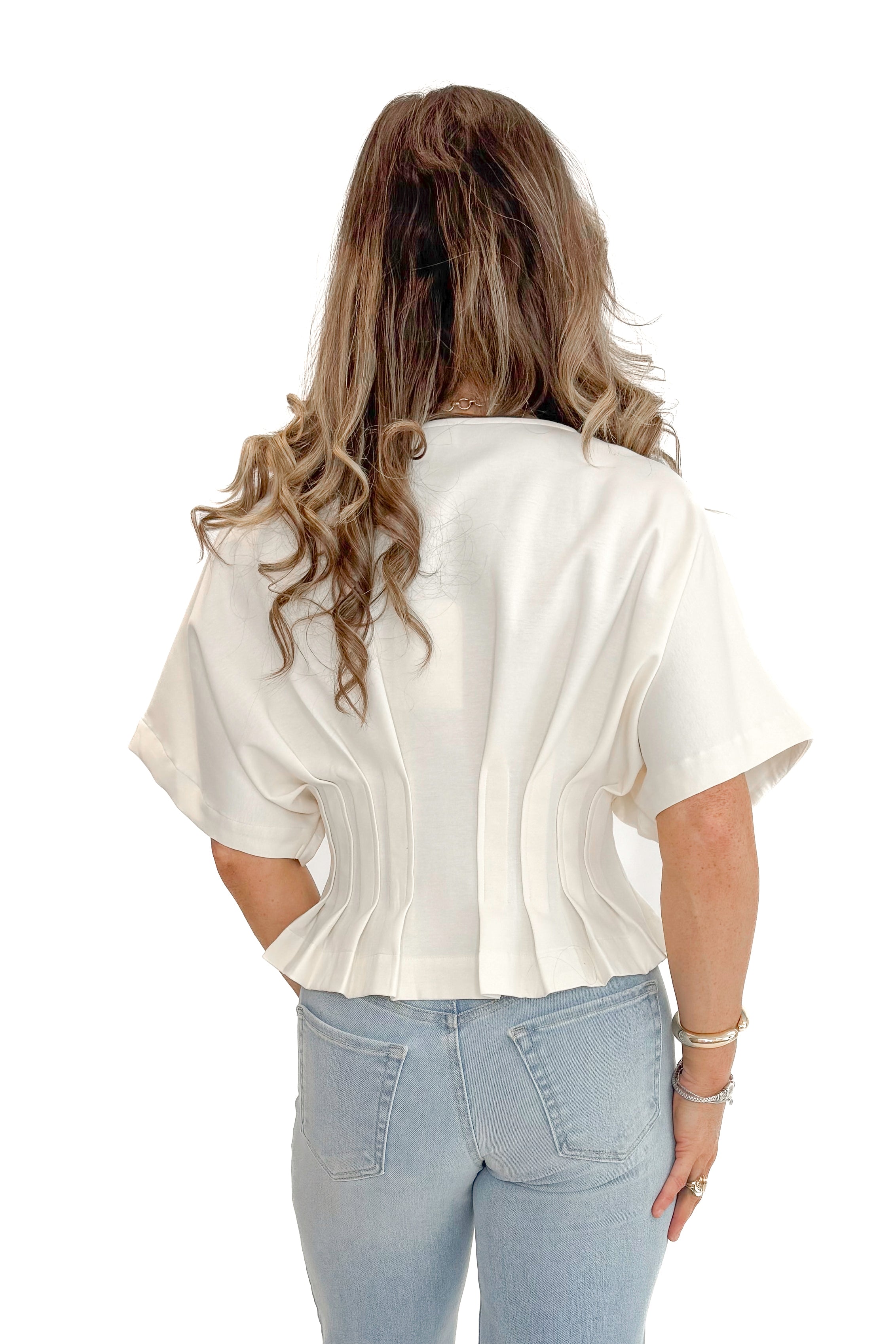 Back view of woman wearing Cream Pleat Detail Dolman Sleeve Top with jeans against white studio background.