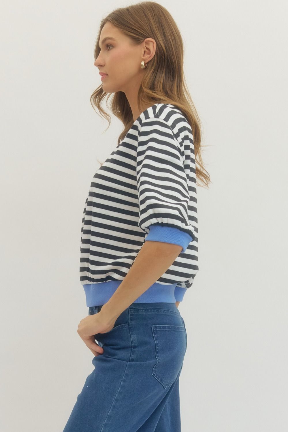 Side view of woman wearing Black Striped With Blue Lining 3/4 Sleeve Sweatshirt by Entro with jeans against a white background.