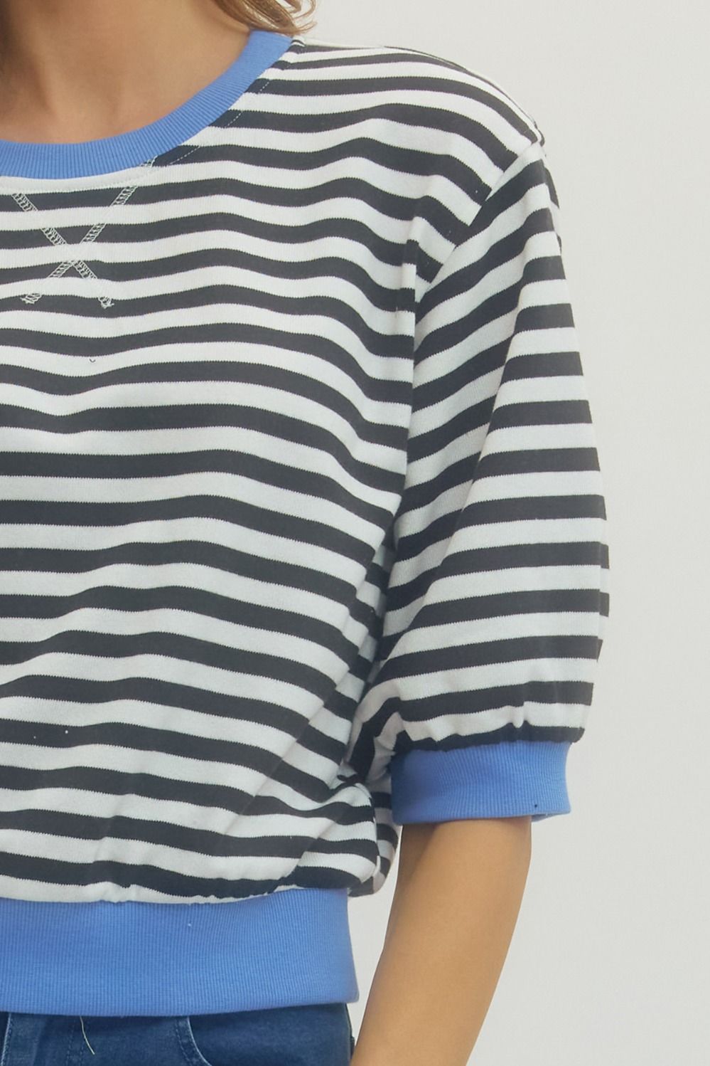 Front detail view of woman wearing Black Striped With Blue Lining 3/4 Sleeve Sweatshirt by Entro with jeans against a white background.