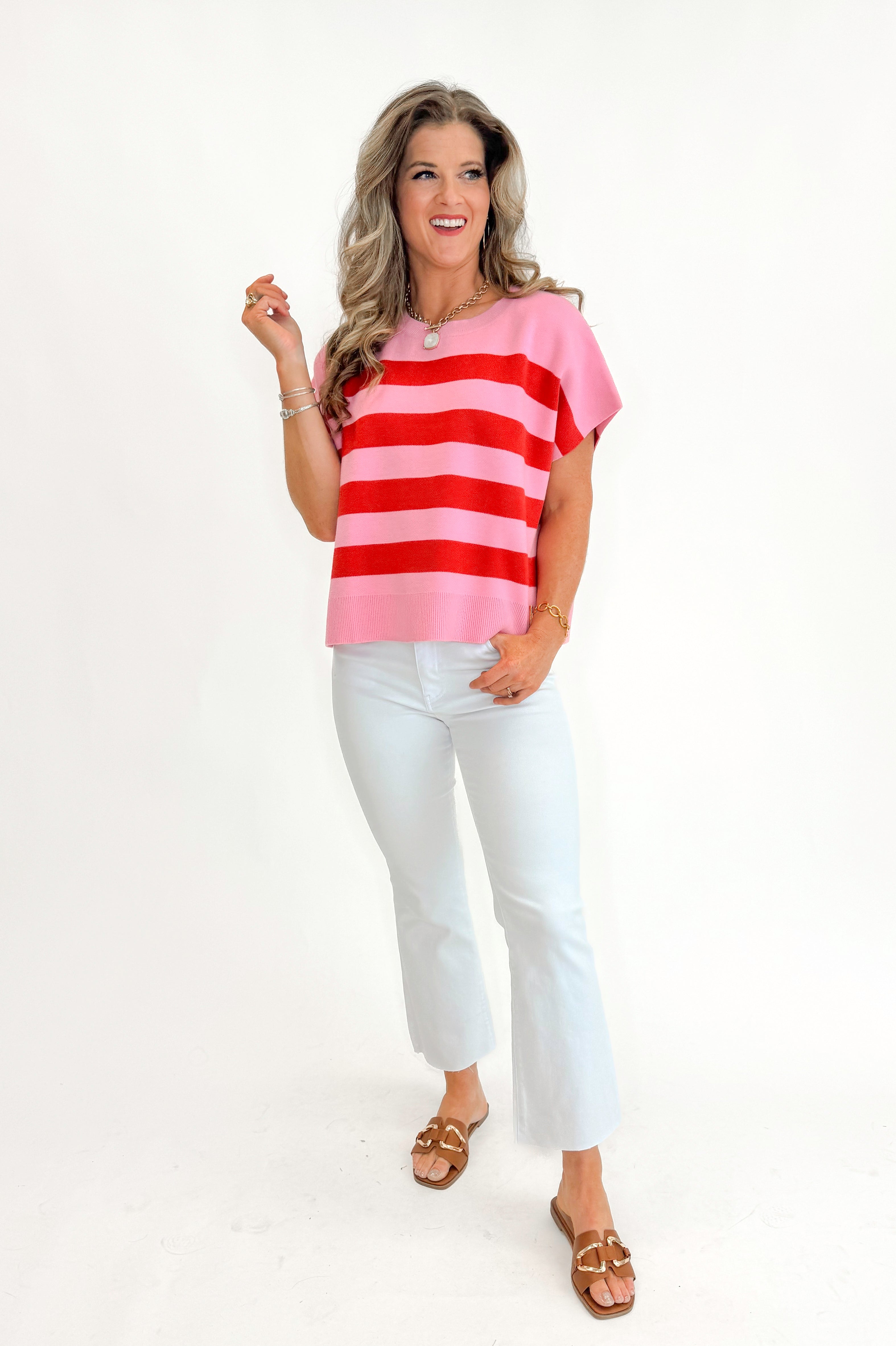 Front view of woman wearing Pink &amp; Red Sleeveless Sweater by Entro with jeans against white studio background.