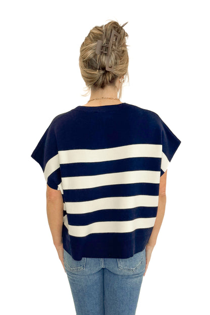 Back view of woman wearing Navy &amp; Cream Sleeveless Sweater by Entro with jeans against white studio background.