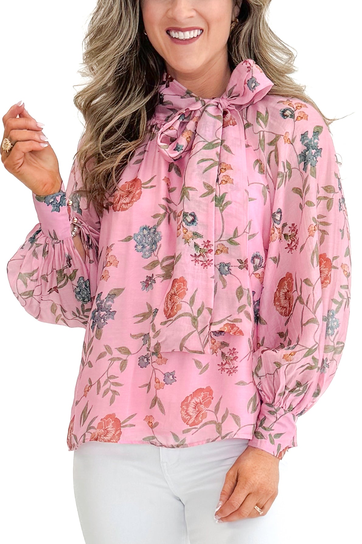 Front detail view of woman wearing Pink Floral Tie Neck Top by Entro with jeans against white studio background.