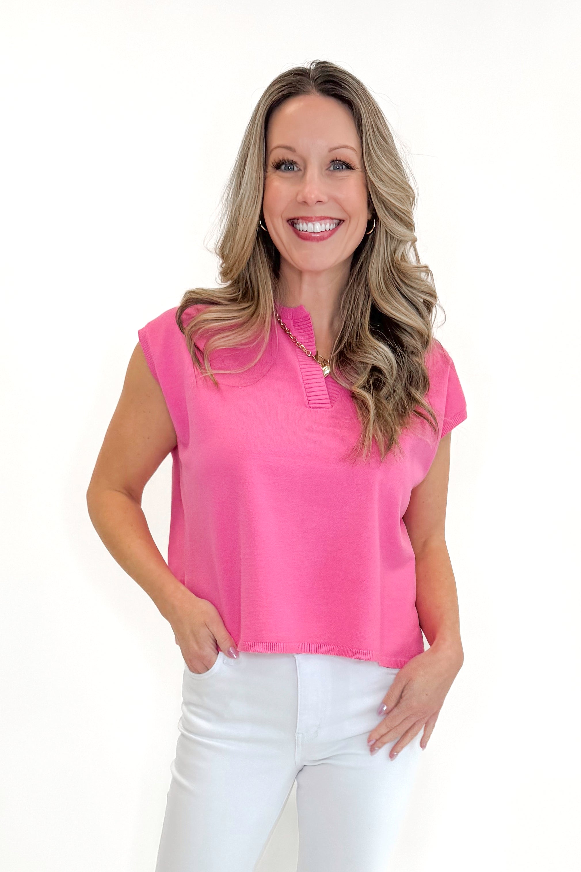Front view of woman wearing Pink Ribbed V-Neck Sleeveless Sweater by Entro with jeans against white studio background.