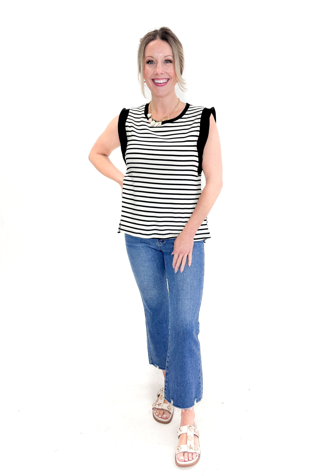 Front view of woman wearing White &amp; Black Striped Sleeveless Top by Entro with jeans against white studio background.
