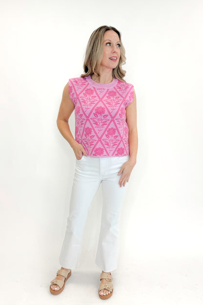 Front view of woman wearing Pink Floral Printed Sleeveless Sweater by Entro with jeans against white studio background.