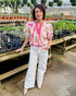 Front view of woman wearing Pink & Tan Paisley Printed Top by Entro with jeans at a garden center.