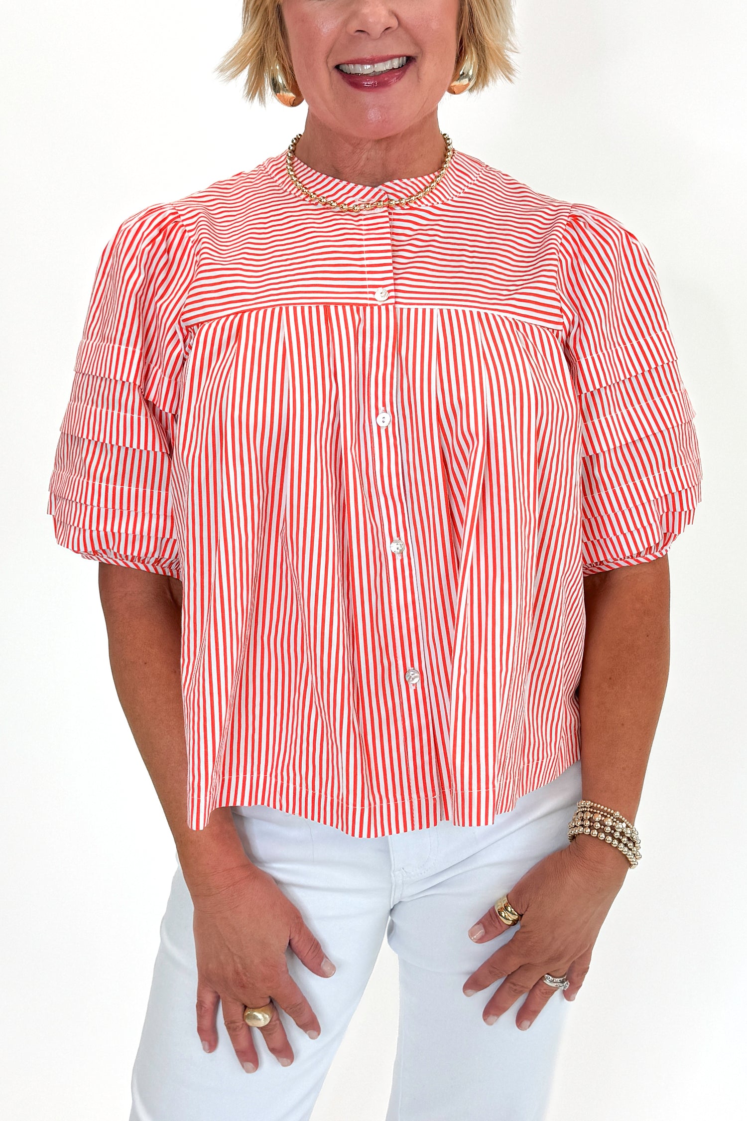 Front detail view of woman wearing Orange Striped Puff Sleeve Top by Entro with jeans against white studio background.