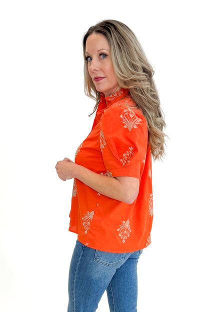 Side view of woman wearing Orange Embroidered Button Up Top by Entro with jeans against white studio background.