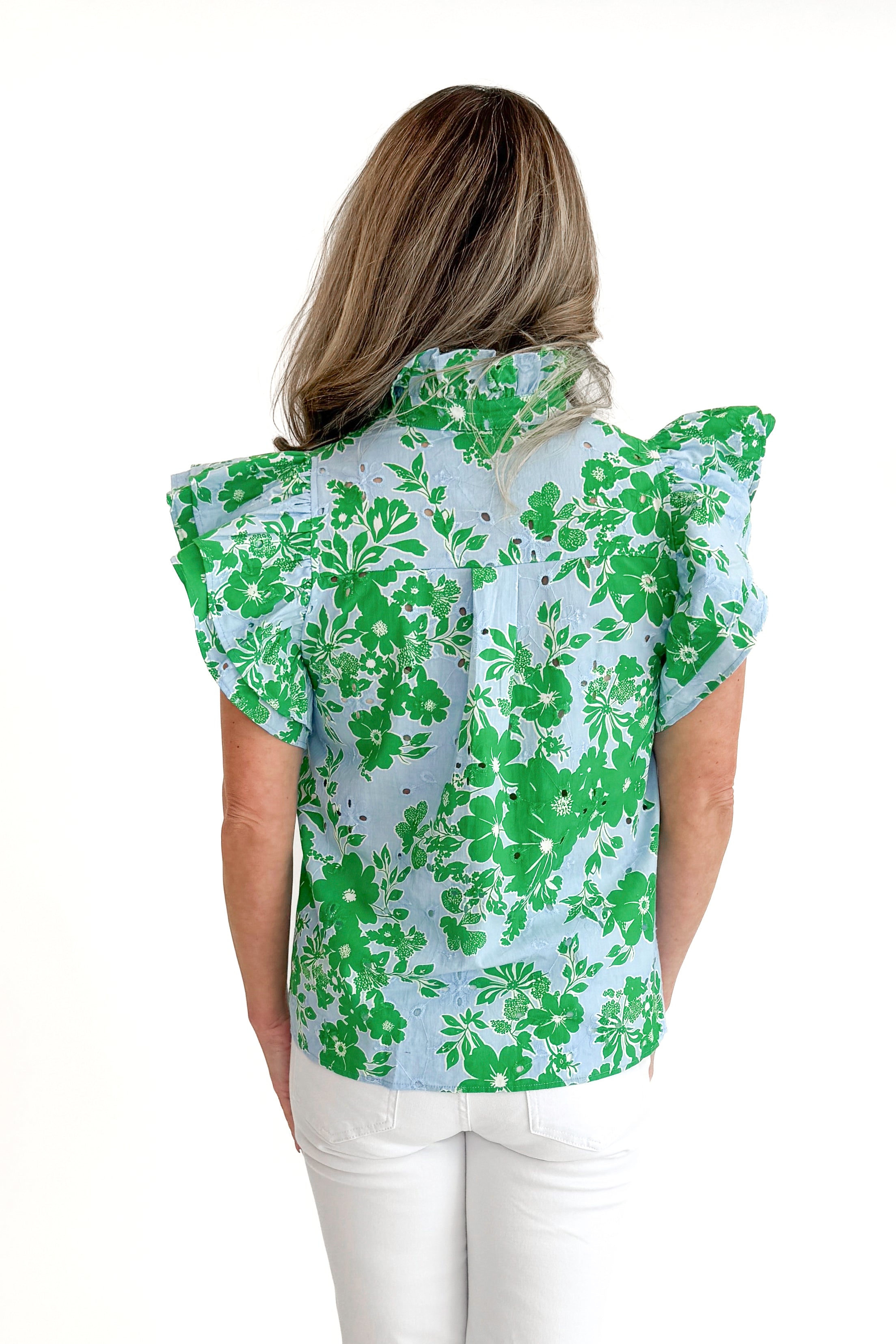 Back view of woman wearing Green &amp; Blue Floral Eyelet Top by Entro with white jeans against white studio background.