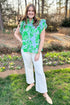 Front view of woman wearing Green & Blue Floral Eyelet Top by Entro with white jeans outside at a garden.