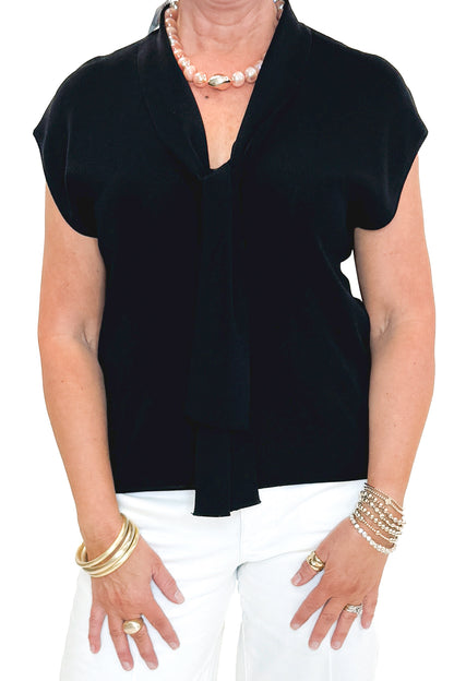 Front detail view of woman wearing Black Faux Layered Sweater Tank by Entro with jeans against white studio background.